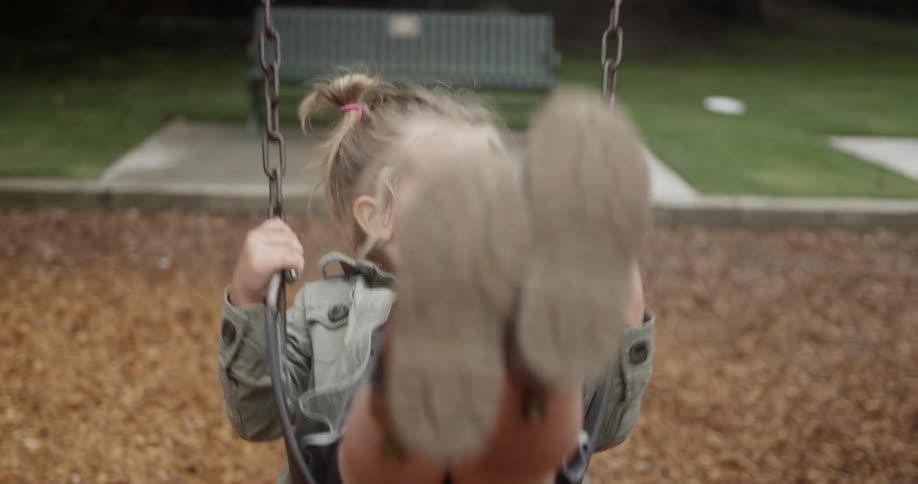 A young girl swings on a park swing set