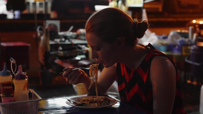 Woman is eating spaghetti in restaurant at night