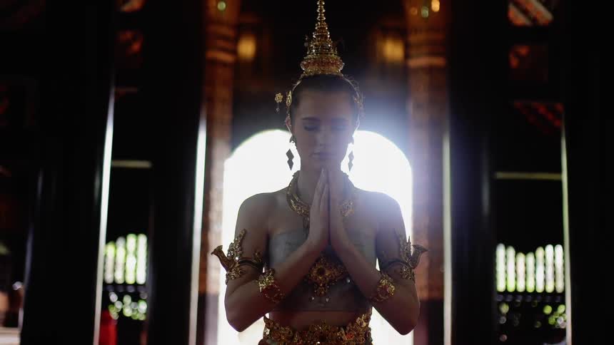 Woman wearing a headdress praying in a temple