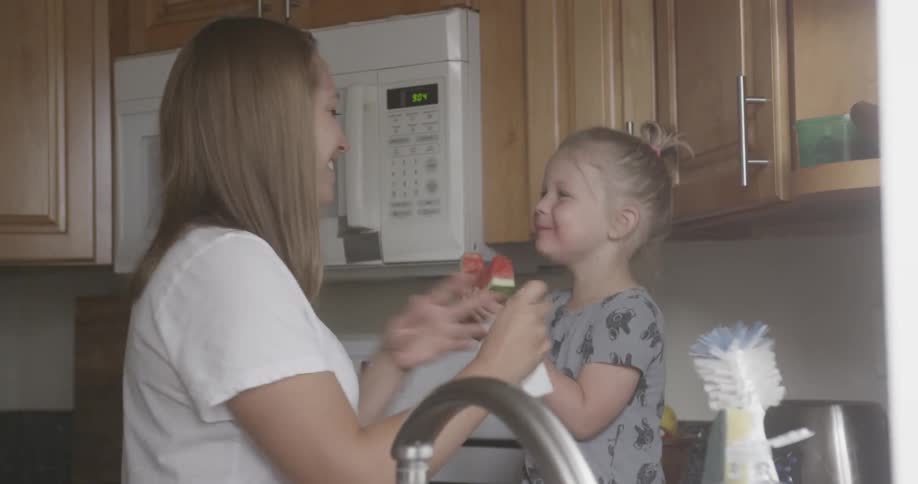 A mom and her daughter laugh in the kitchen