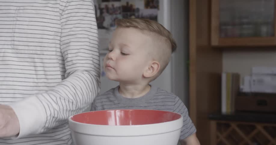 Toddler helps his mother put powder into a bowl