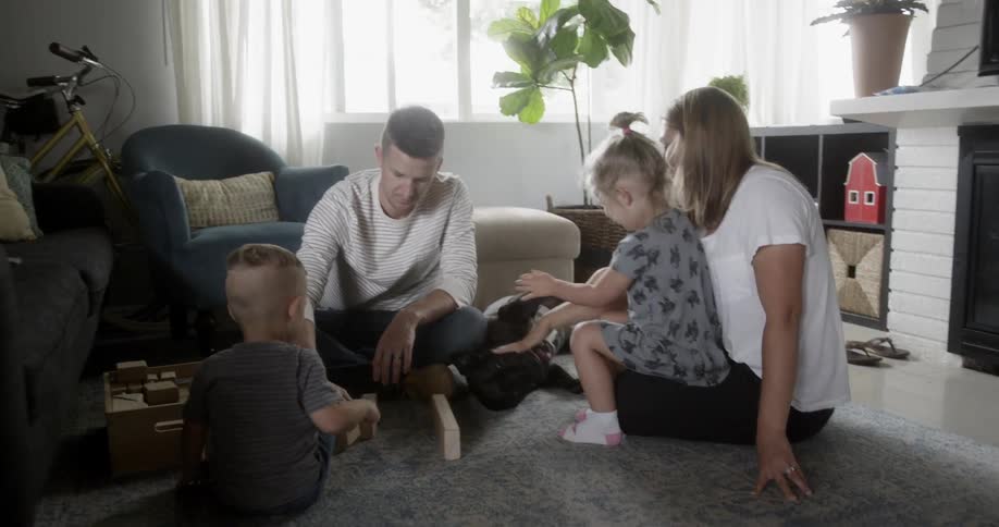 Man woman and children sit in a living room with a dog