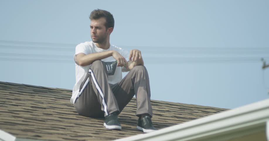 A man smokes a cigarette alone on a roof