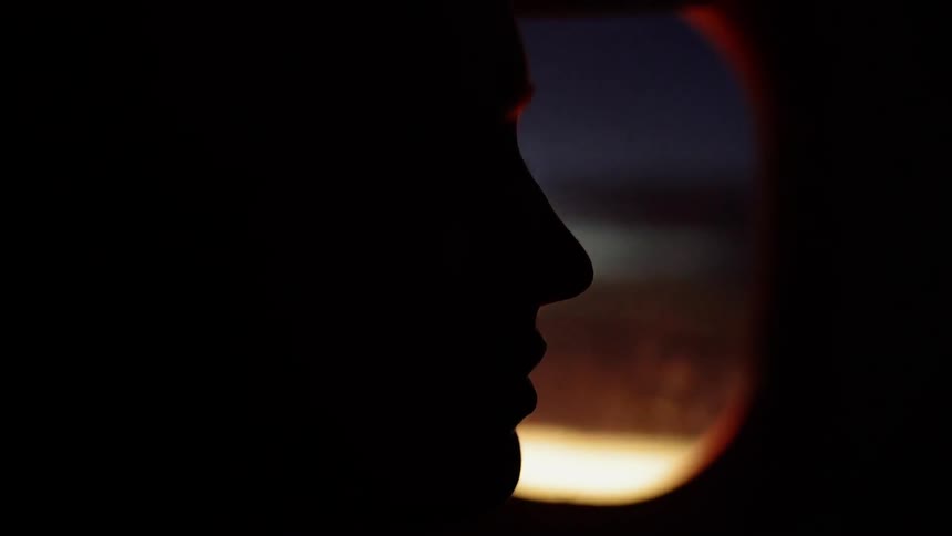 A person rides in an airplane at dusk