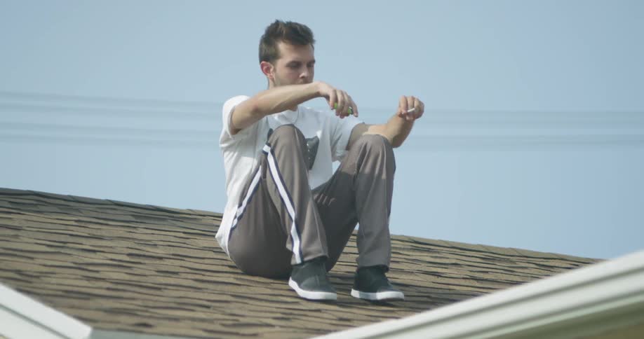 A man smokes on the roof