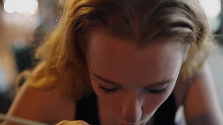 A woman eats noodles with chopsticks