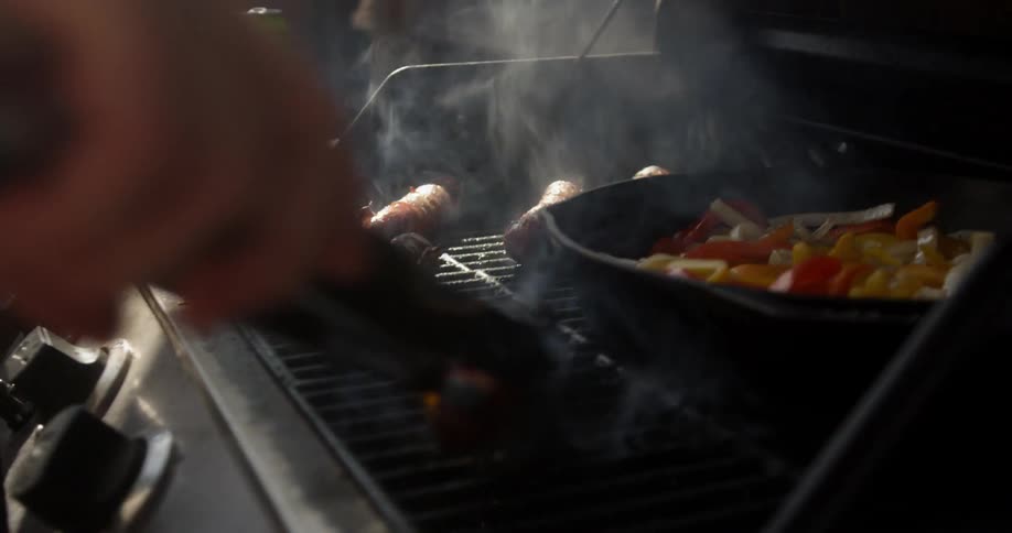 Hot dogs and vegetables are cooked on a grill