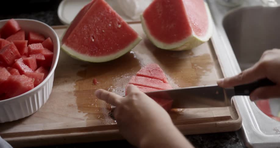 A woman slices watermelon
