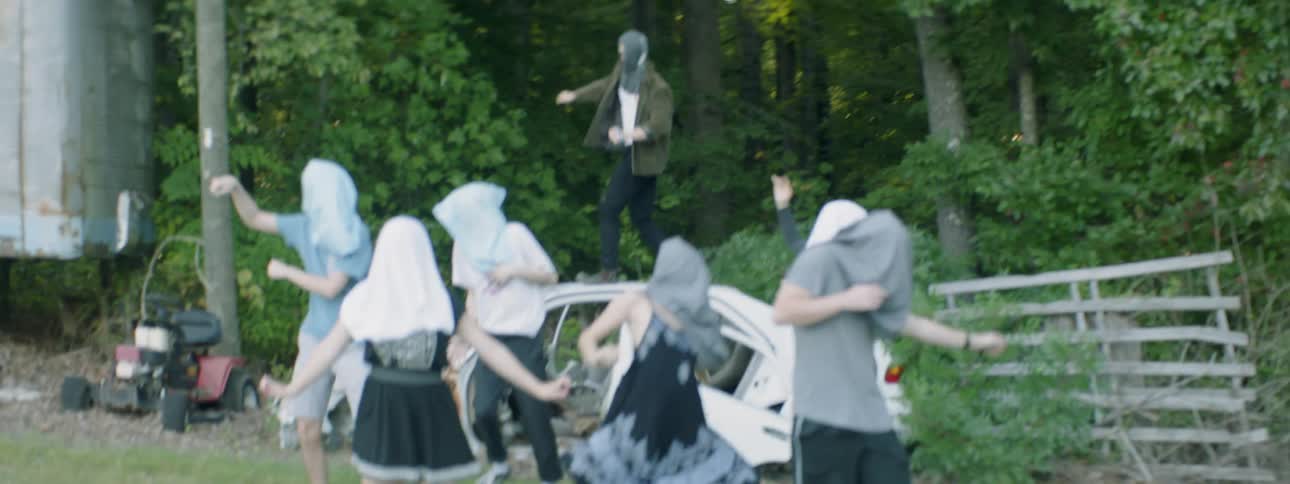 People dance outside with bags covering their faces