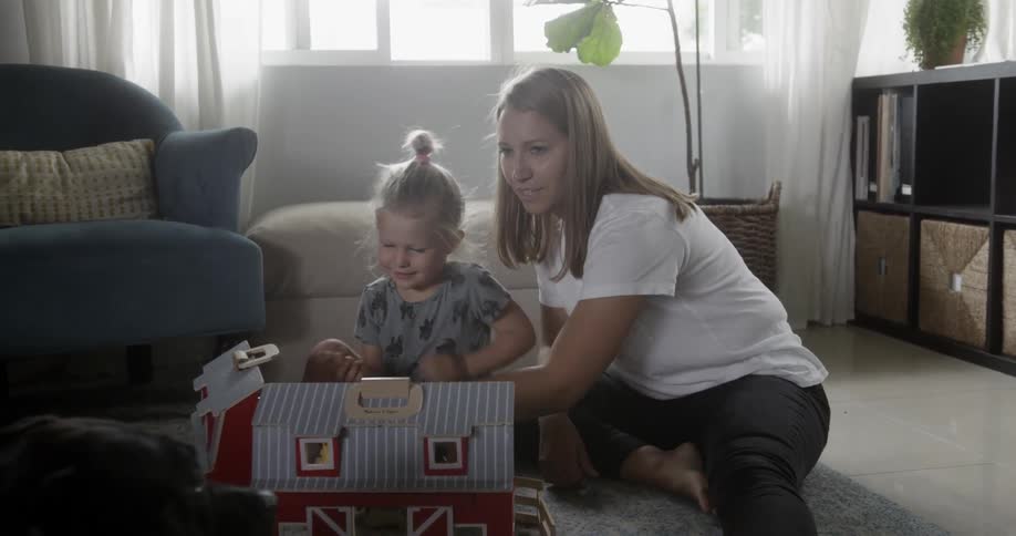 A woman plays with her daughter and dog in the living room