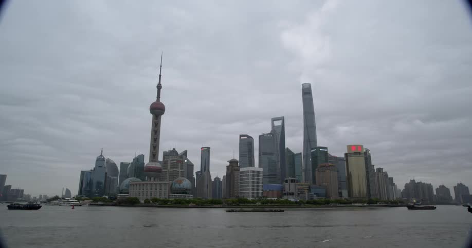 Boats are traveling across bay in front of large city on cloudy day