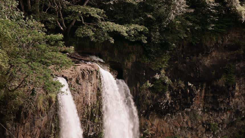 Waterfall flowing off edge of rock cliff on sunny day