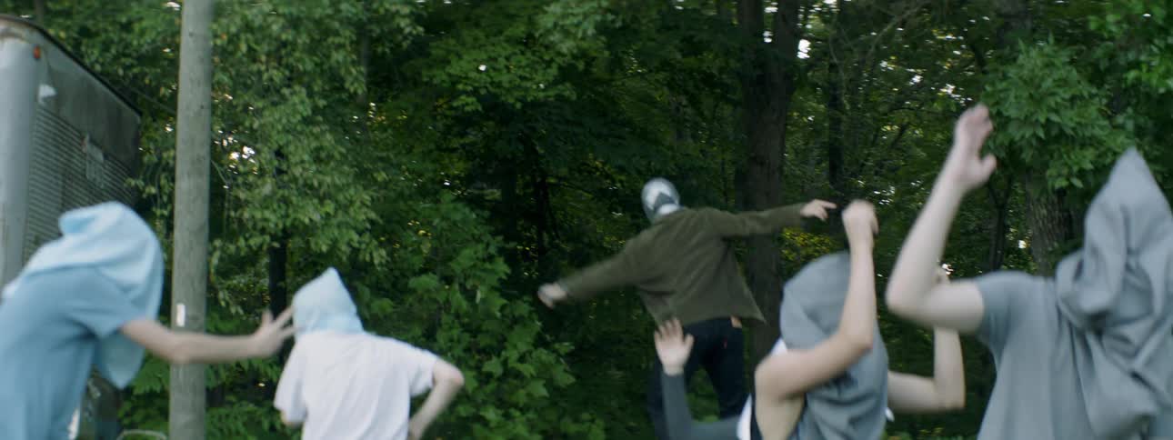People dance outside with bags covering their faces