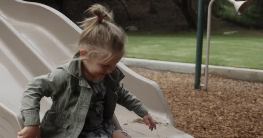 Young girl slides down a slide in the park