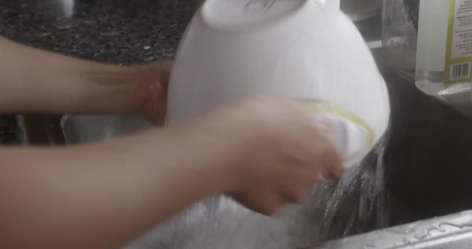Person washes a bowl in the sink