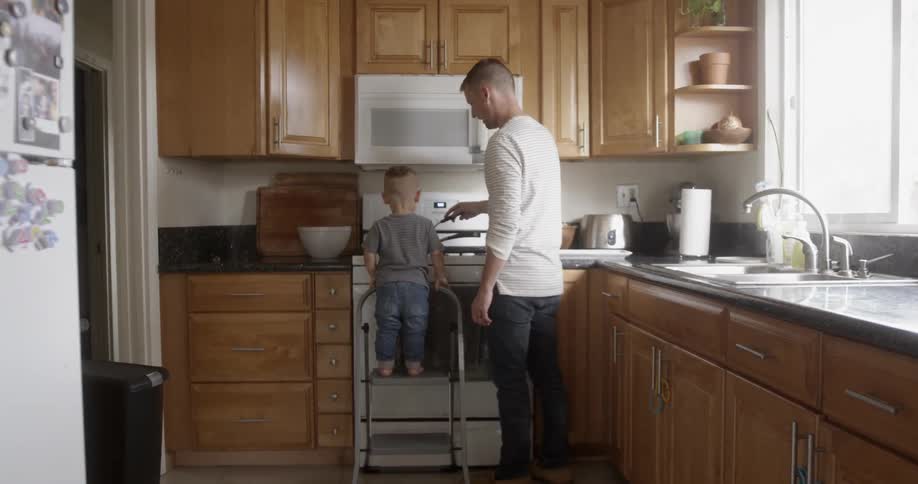 A father cooks in the kitchen with his young son