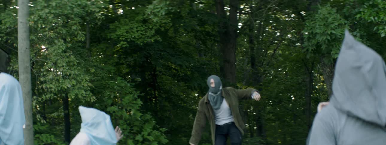 People wearing hoods dance in the forest