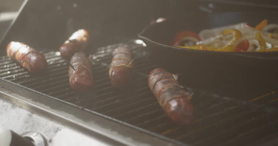 Sausages and peppers cook on the barbecue