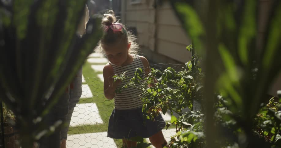 Adult and child look at a plant in a garden and walk away