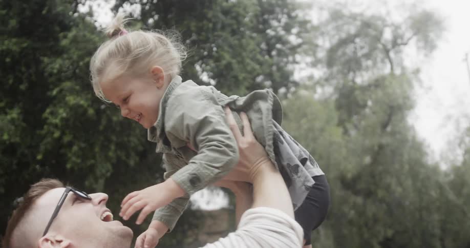 A father playfully throws his daughter in the air