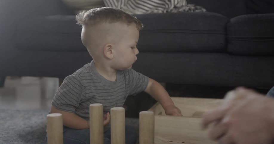 A young boy plays with wood block toys at home