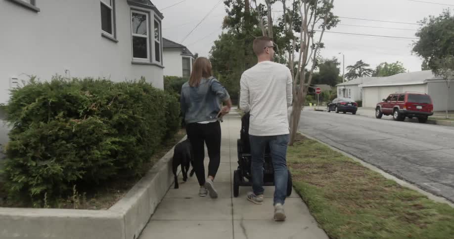 A family walks their dog on a sidewalk