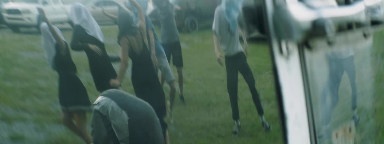 People dance outside with bags covering their faces