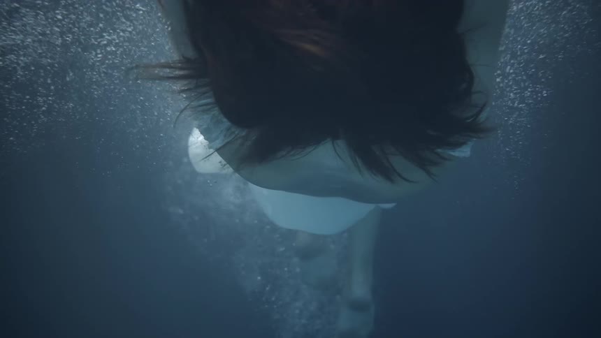 Person wearing a white dress floats underwater