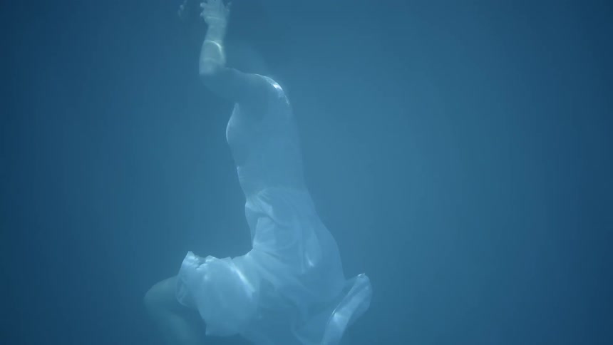 A woman slowly swims around underwater