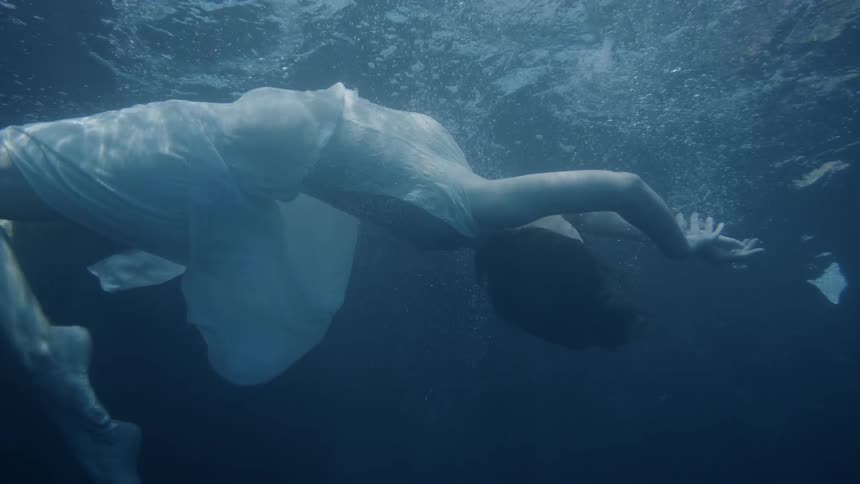 A woman swims around under the water