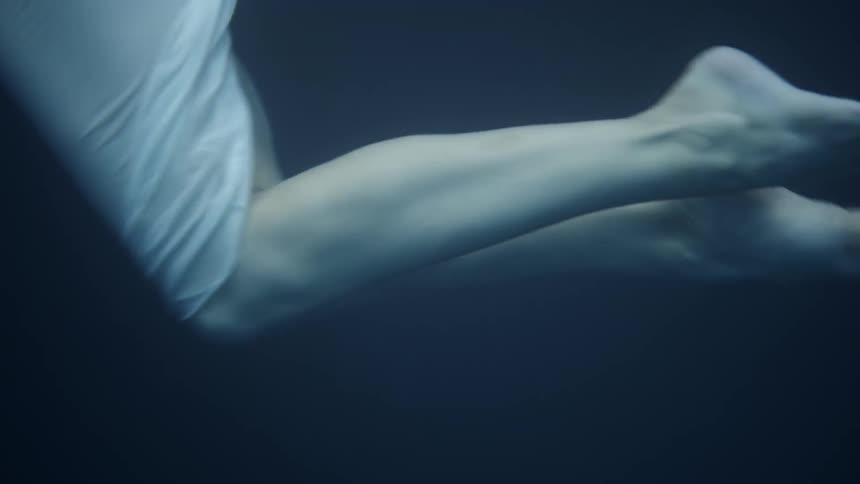 A woman is pointing her toes as she floats underwater in daylight