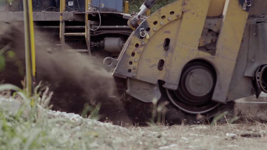 A stump grinder kicks up dust and dirt
