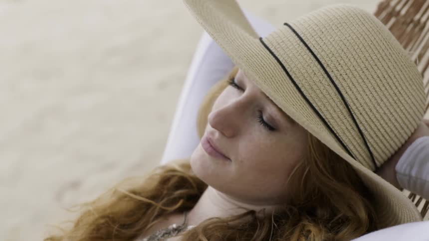 Woman is sleeping on hammock on beach