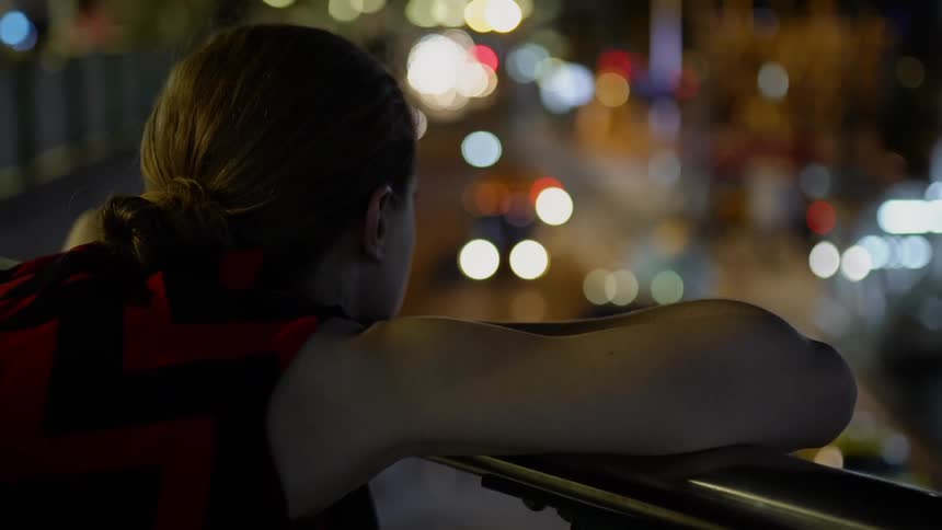 A person looks out onto traffic from the bridge