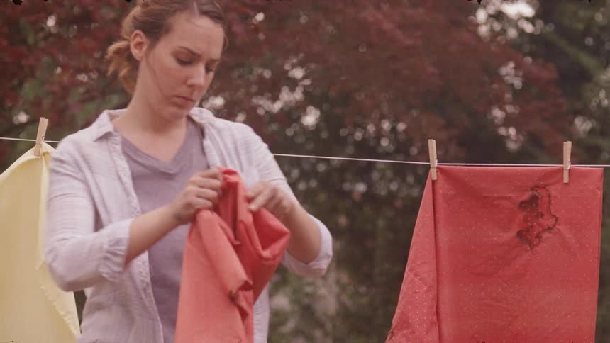 Woman removes clothes from the clothesline and folds them