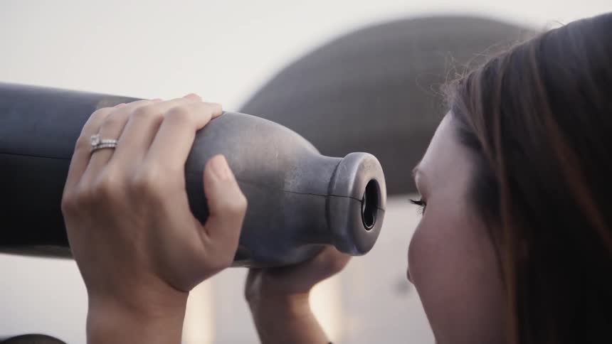 A woman looks through a tourist telescope