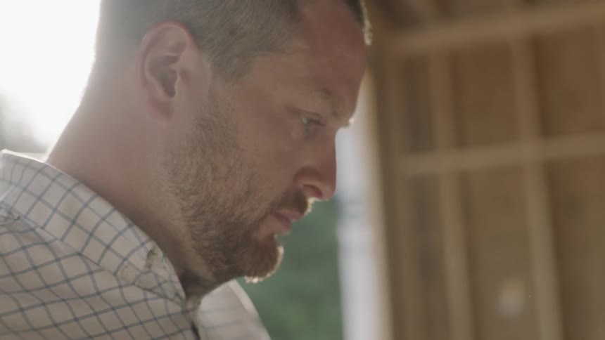 Man Looks At Blueprints For A Construction Site