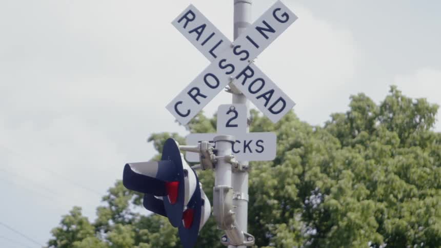 The lights at a railroad crossing flash red