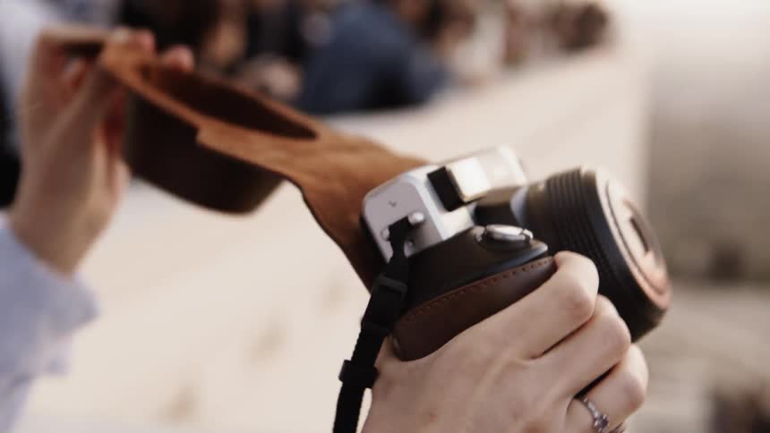 A woman is taking the case off her camera outside in daylight