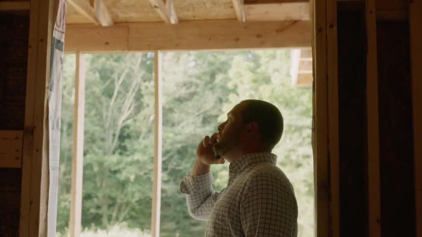 A man talks on a phone at a construction site