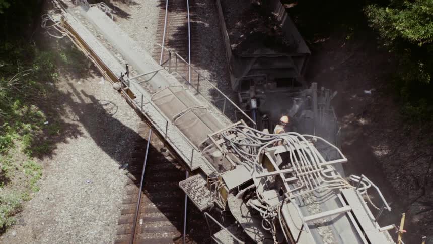 Rocks are flowing down a chute in a dredging operation during the day