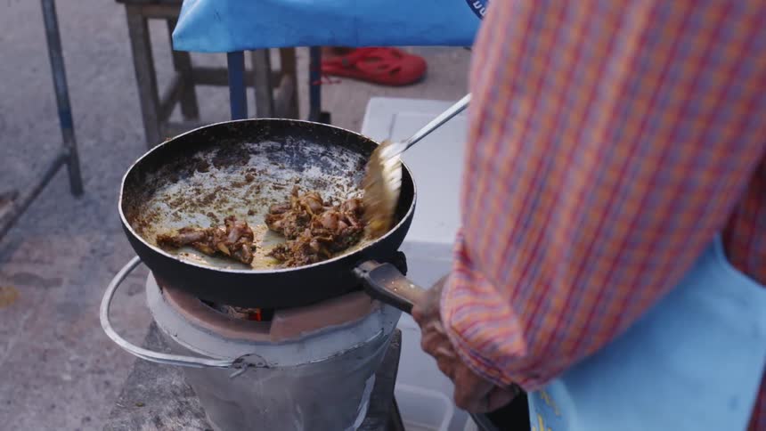 The food is being tossed in the pan outside