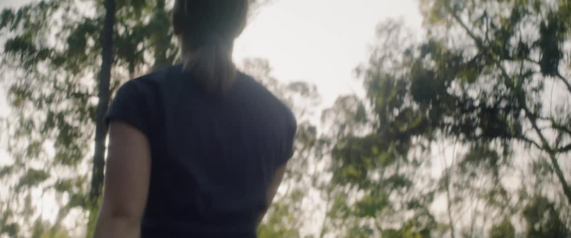 Woman walks through the woods on a sunny day