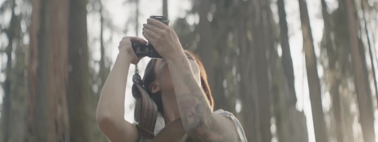 A woman takes photos in a sunny forest