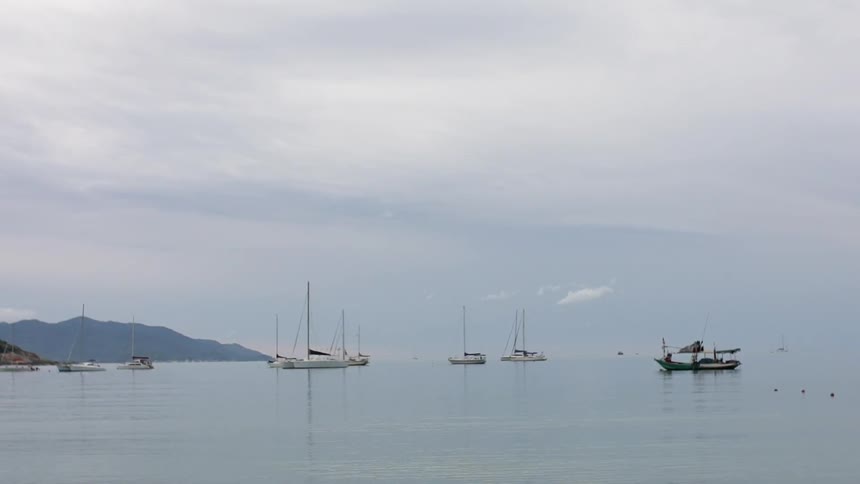Boats are floating anchored in a bay on a cloudy day