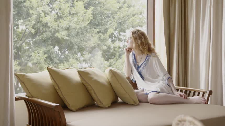A woman relaxes on a couch with pillows