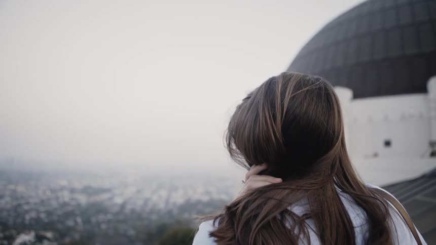 A woman overlooks a city on a hazy day
