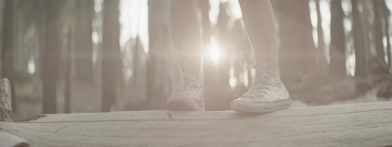 Person stands on a wooden step outside in the sunlight