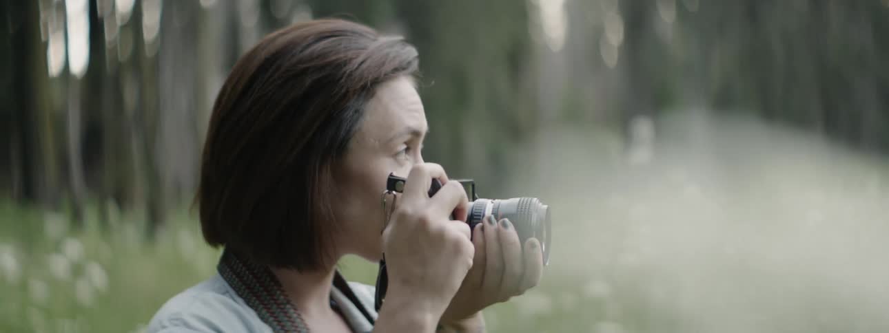 A woman takes photographs in the tall grass