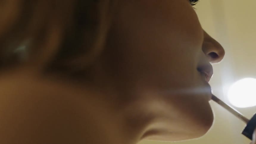 A woman is putting on lip gloss in a well lit room